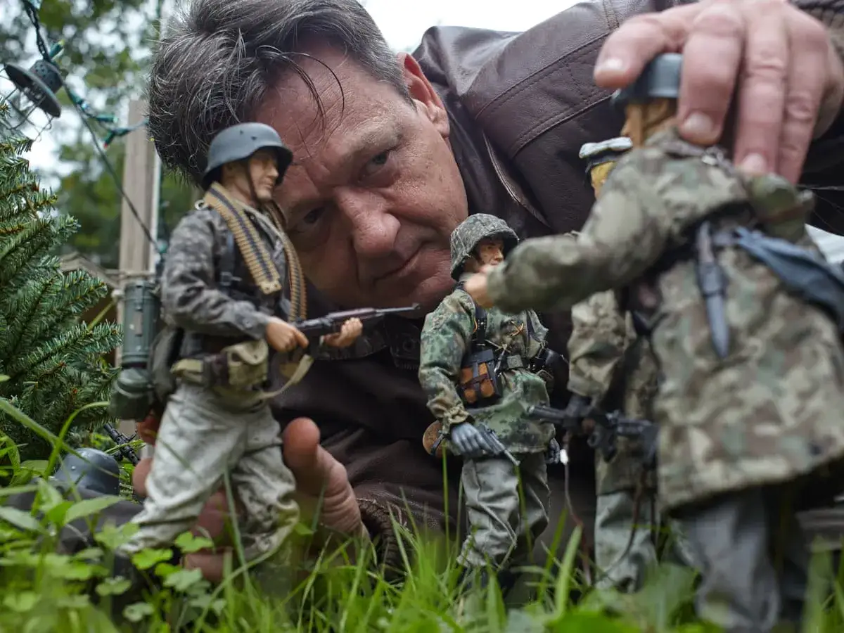 Mark Hogancamp dirige una escena de guerra con figuras de soldados en miniatura, creando un mundo detallado en su jard&iacute;n.