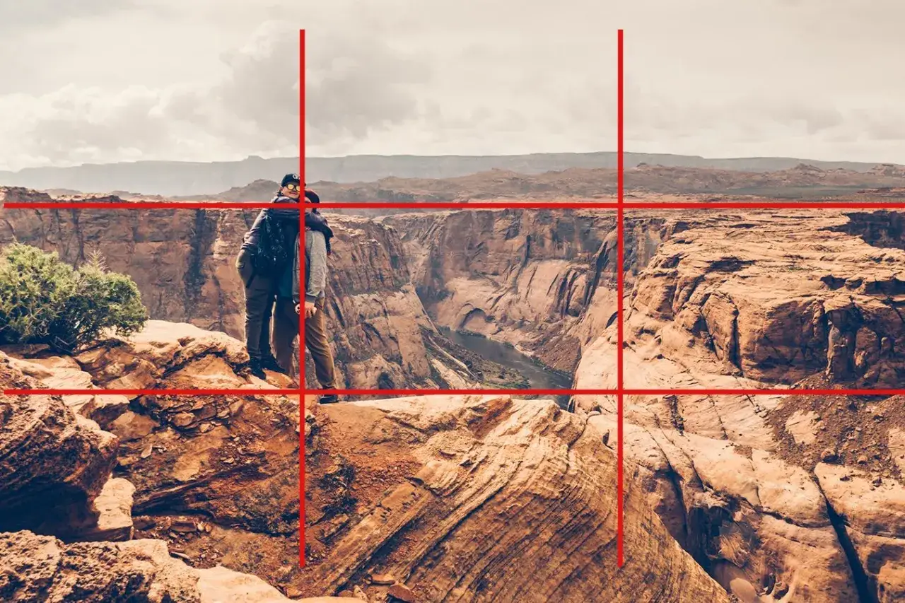 Pareja abrazada en un cañón, con líneas rojas que sugieren una composición en fotografía para resaltar la inmensidad del paisaje.