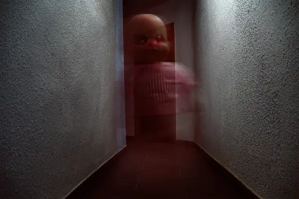 Un muñeco con ojos rojos y cejas verdes aparece en un pasillo oscuro. Son fotos que dan mucho miedo.