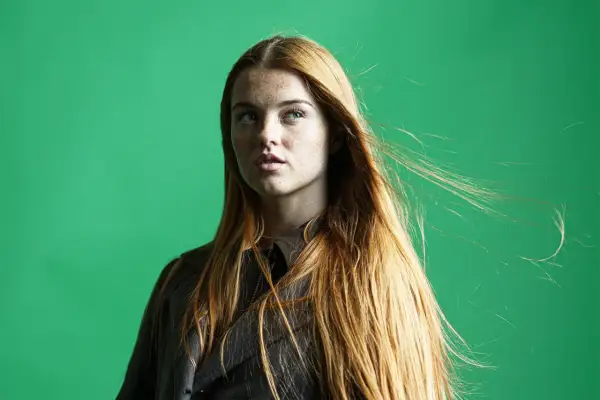 Mujer pelirroja con pecas, su cabello largo y suelto se mueve con el viento. La edición de **dodge and burn** resalta sus rasgos.