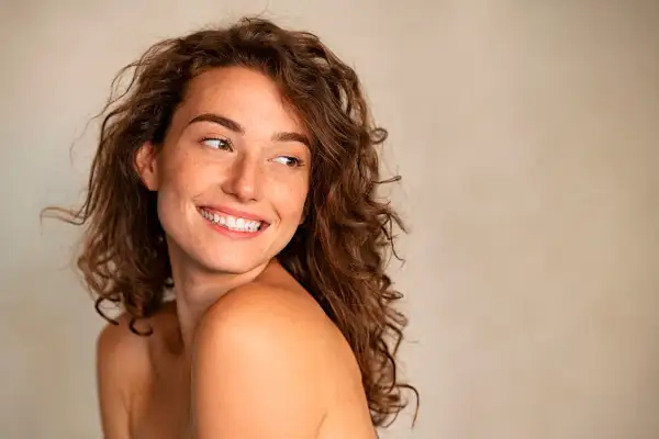 Mujer sonriente con pecas, cabello rizado y mirada radiante. Sigue la regla de la mirada para capturar su belleza natural.