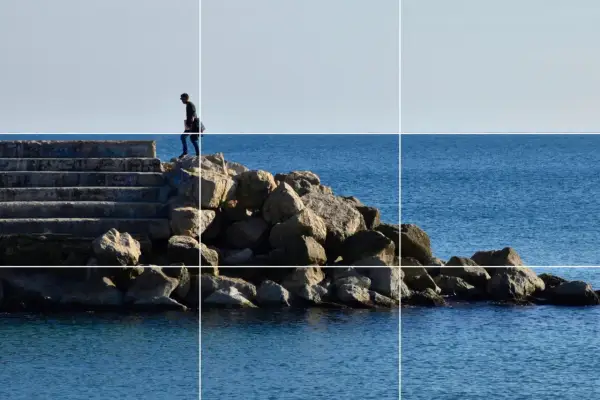 Un hombre camina por unas escaleras de piedra hacia el mar, siguiendo la regla de los tercios vertical.