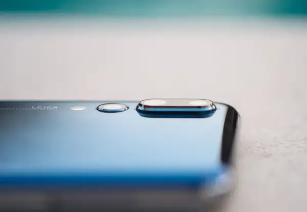 Detalle de la cámara de un smartphone azul, mostrando el módulo de lentes Leica y la tecnología de pixel binning para capturar más luz.