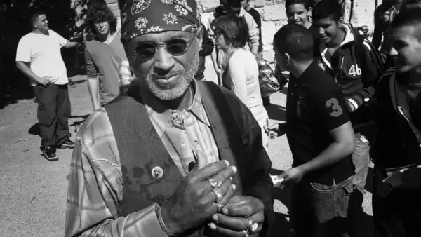 Stanley Greene, con su bandana y anillos, sonríe rodeado de jóvenes.