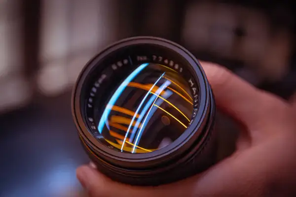 Primer plano de un objetivo de cámara vintage, reflejando luces de colores.