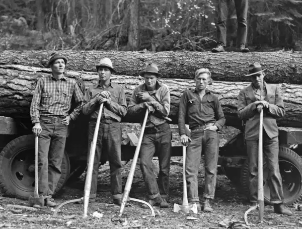 Cinco leñadores posan con sus herramientas junto a un tronco, capturados por Dorothea Lange.