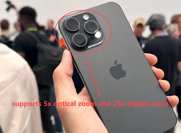 Mano sostiene un iPhone oscuro, mostrando su sistema de cámaras. El texto indica "zoom digital" de 25x y zoom óptico de 5x.