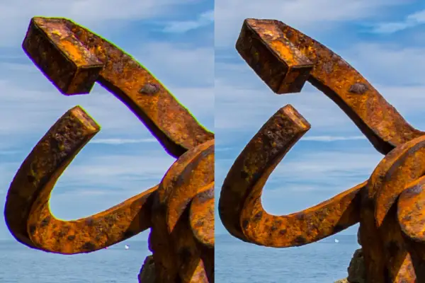 Escultura de metal oxidado con aberración cromática visible en los bordes, contra un cielo azul y mar.